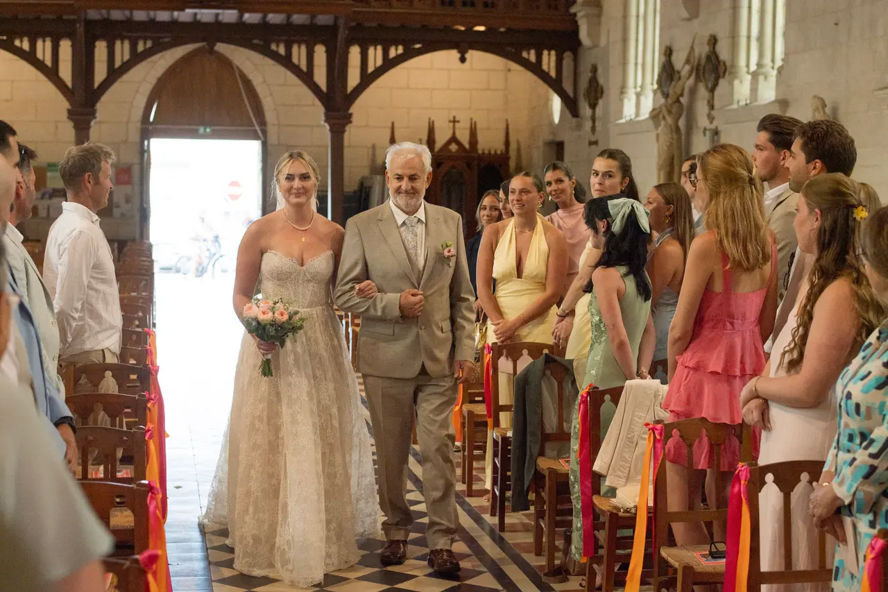la mariée entre dans l'allée au bras d'un invité, assistance debout