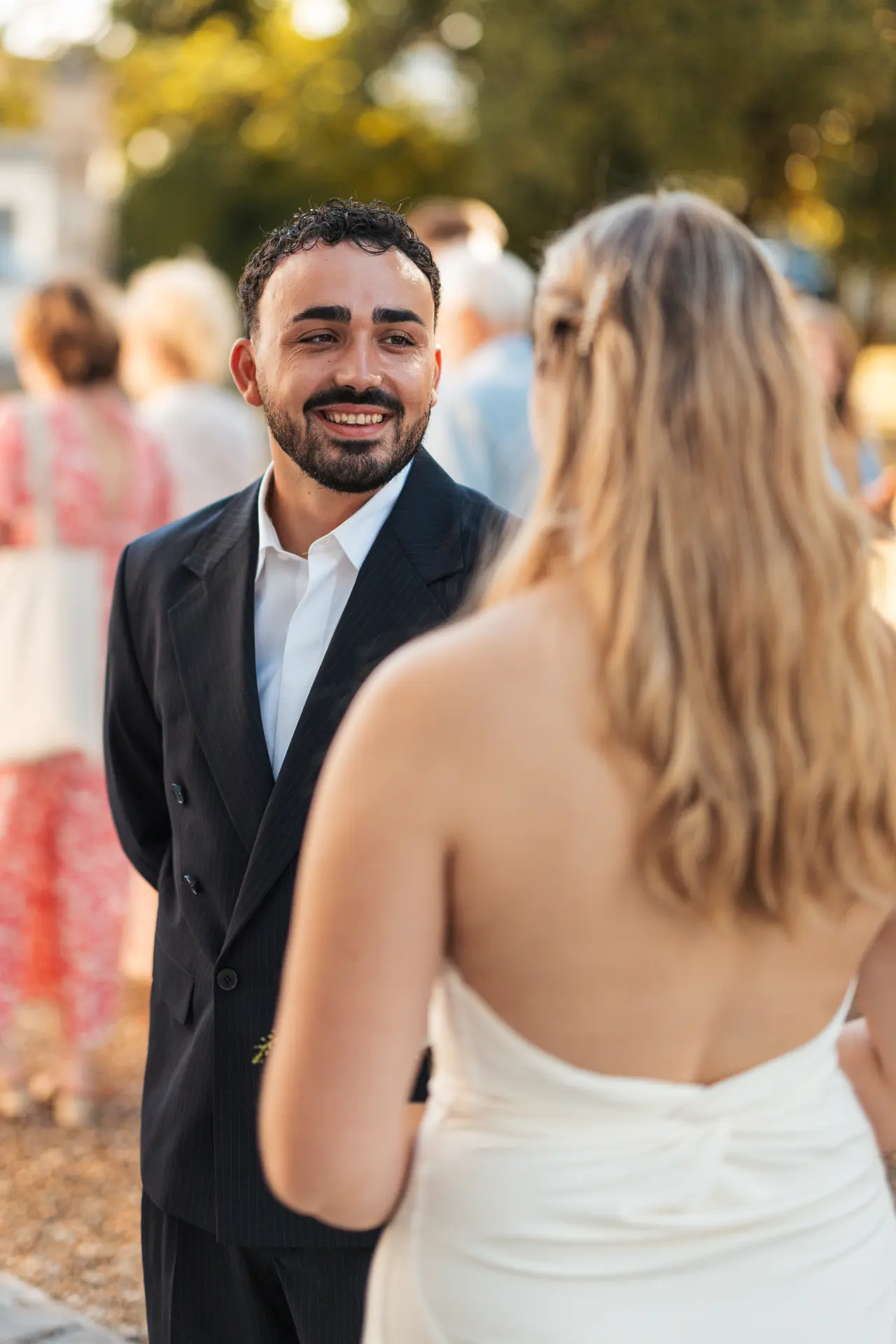 le marié sourit par-dessus l'épaule de la mariée