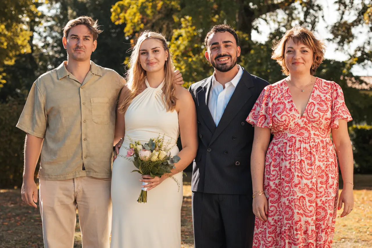 Les mariés, un invité en chemise beige et une invitée en robe rouge