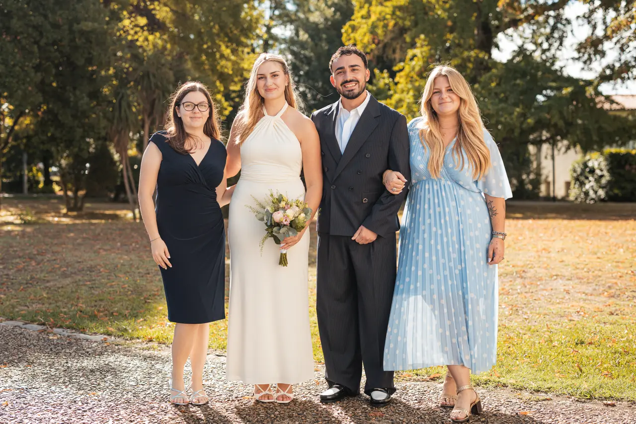 Les mariés et deux invitées, l'une en robe bleu marine, l'autre en robe bleu clair