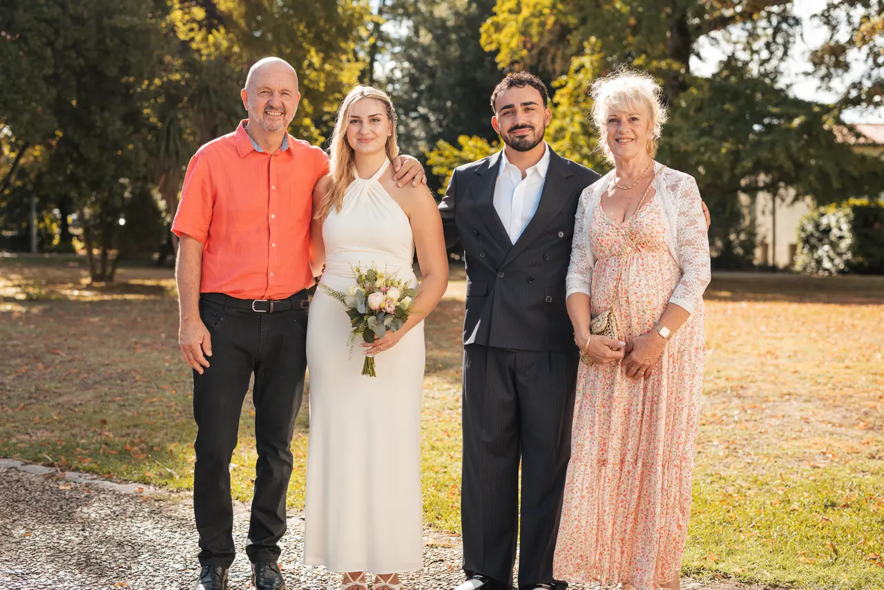Les mariés, un invité en polo orange et une invitée en robe rose
