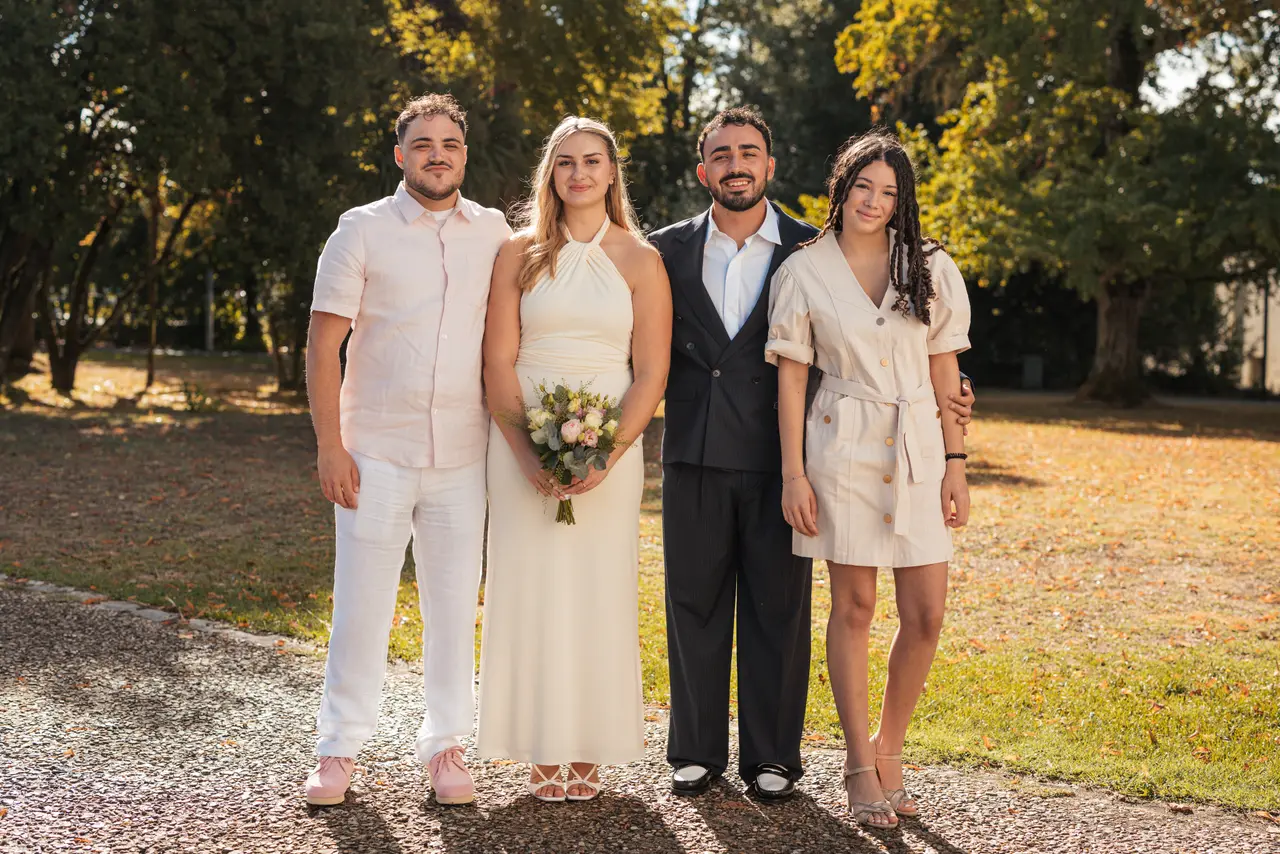 Les mariés, un invité en chemise rose pâle et une invitée en robe beige