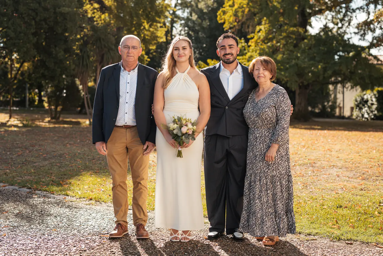 Les mariés, un invité en veste bleu marine et une invitée en robe grise
