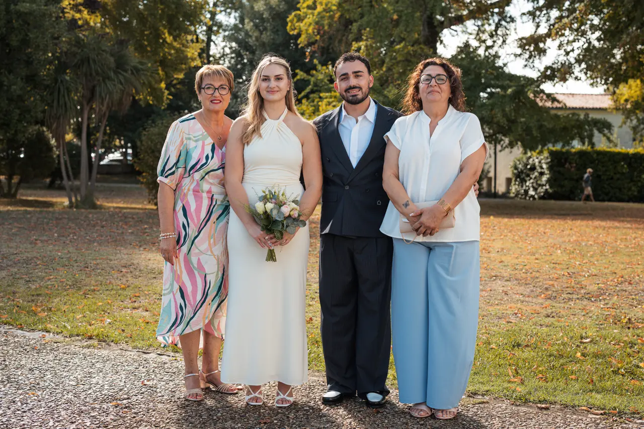Les mariés et deux invitées, l'une en robe colorée, l'autre en chemisier blanc