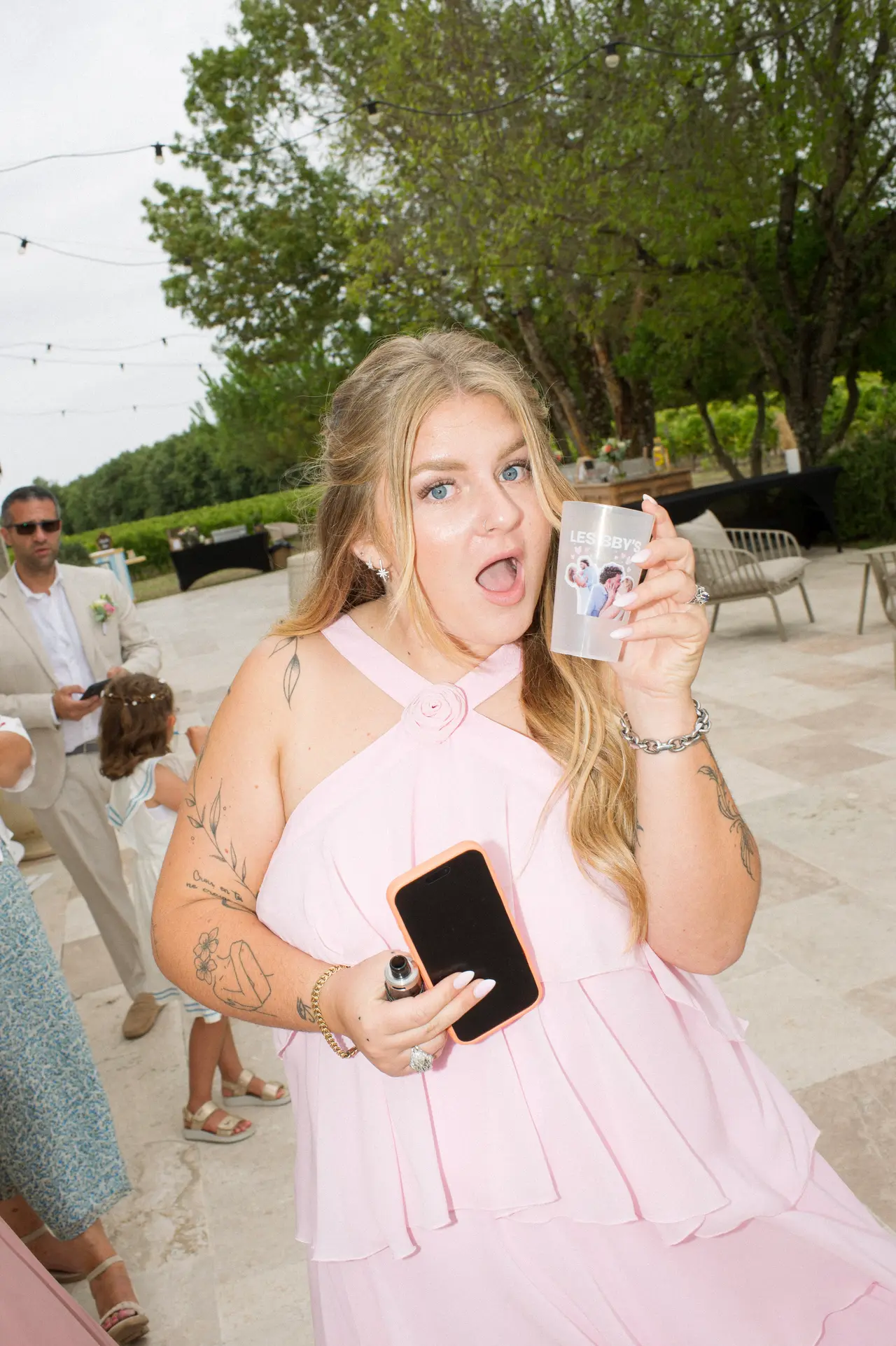 invitée en robe rose, grimace joyeuse derrière son verre