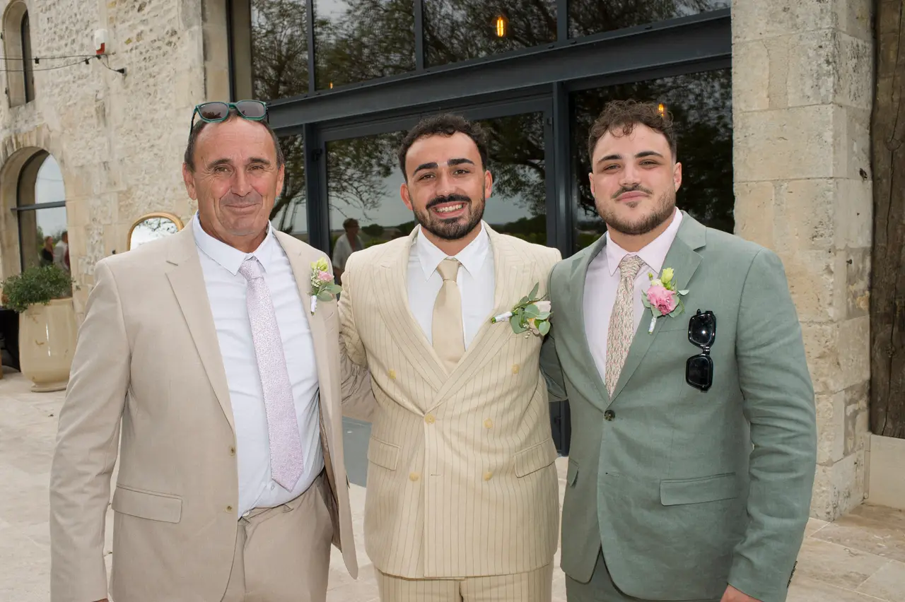 trois hommes côte à côte, costumes beige, crème rayé et vert sauge, terrasse en pierre