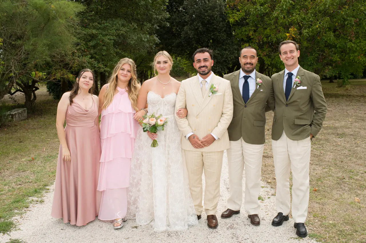 six personnes alignées autour des mariés, robes roses et vestes kaki, allée arborée