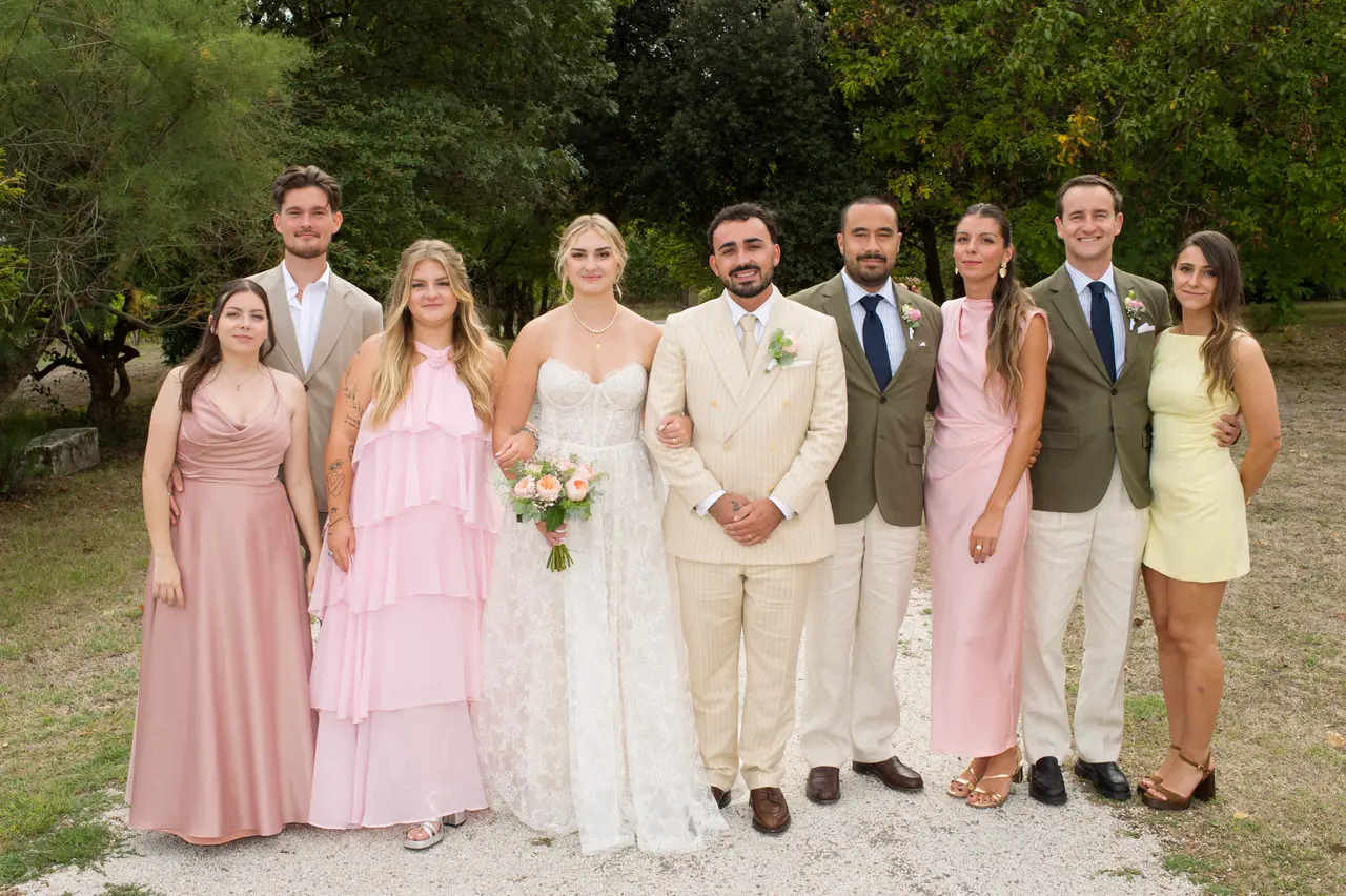 neuf personnes autour des mariés, robes rose et jaune, vestes kaki, allée arborée