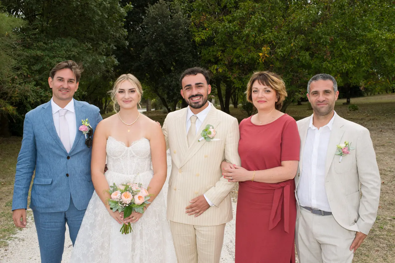 mariés avec un costume bleu, une robe rouge brique et un costume crème, parc