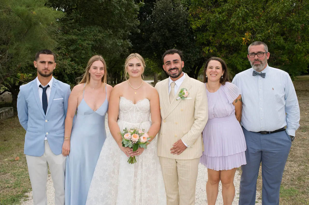 six personnes autour des mariés, robes bleu ciel et lilas, nœud papillon, parc