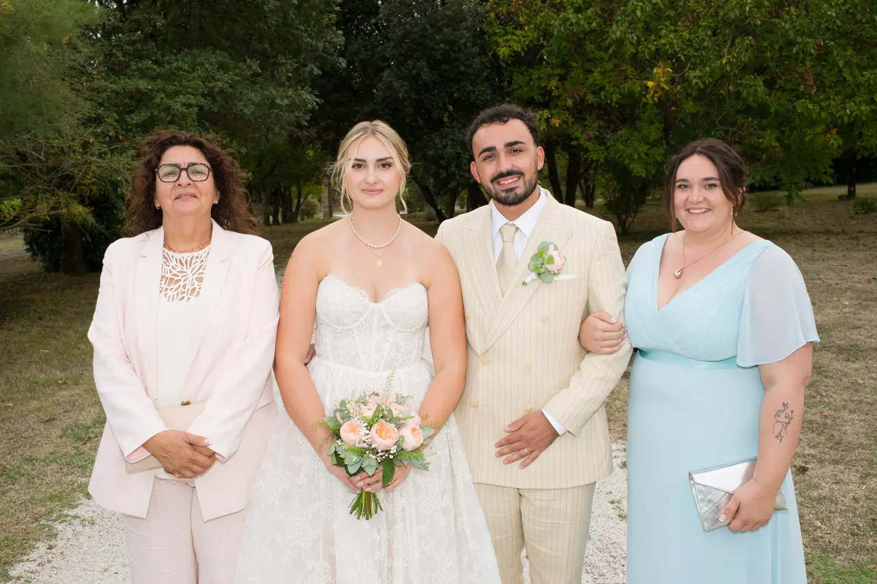 les mariés entre une femme en tailleur rose pâle et une femme en robe bleu ciel