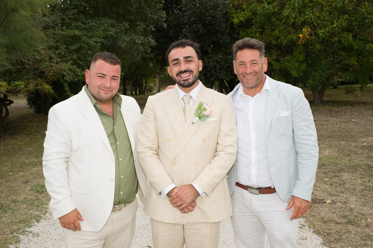 le marié entre un homme en veste blanche et chemise verte et un homme en veste bleu clair