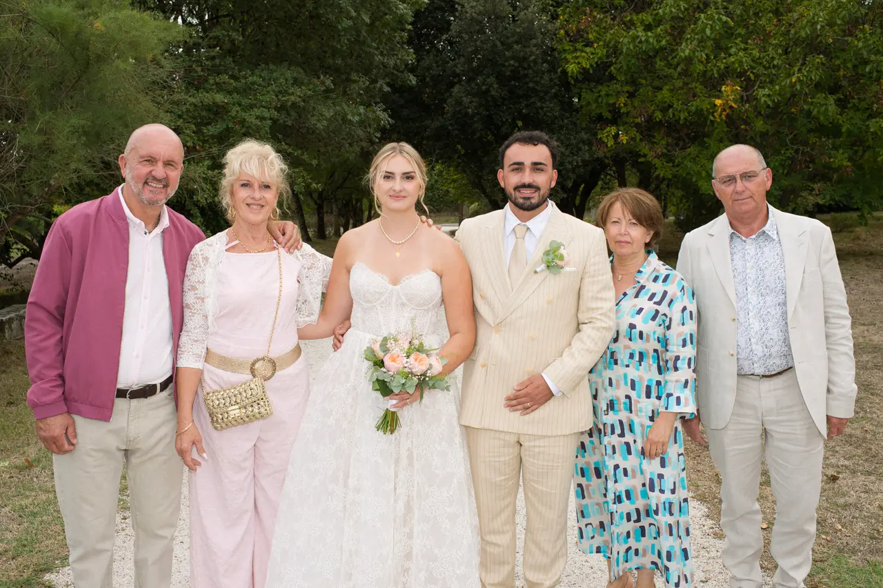 six personnes en ligne autour des mariés, veste framboise, robe à motifs turquoise, parc arboré