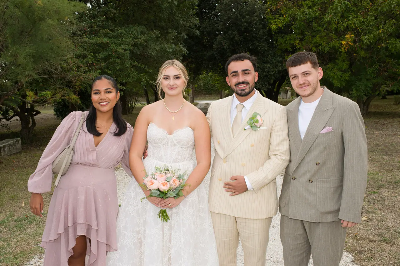 les mariés entre une femme en robe vieux rose et un homme en costume taupe