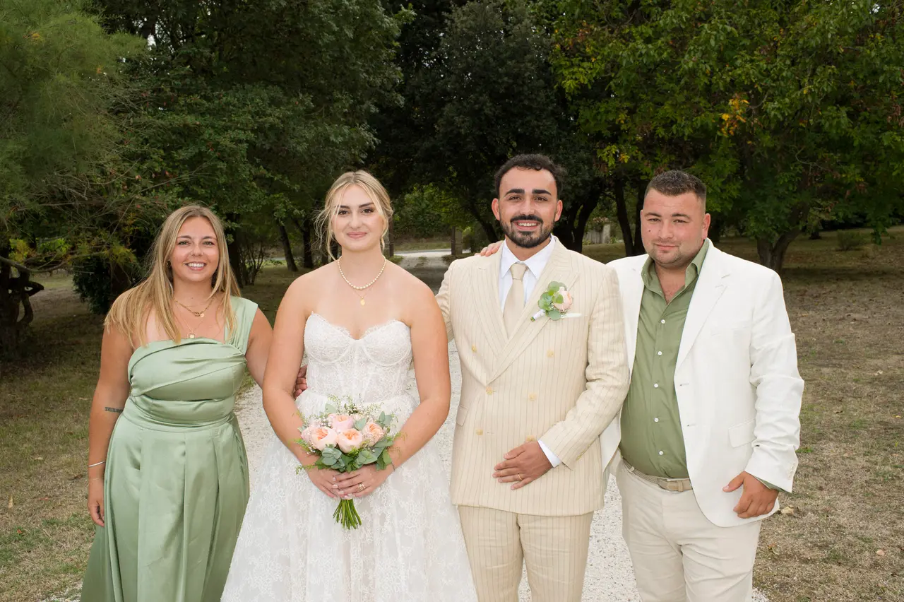 les mariés entre une femme en robe satin vert sauge et un homme en veste blanche