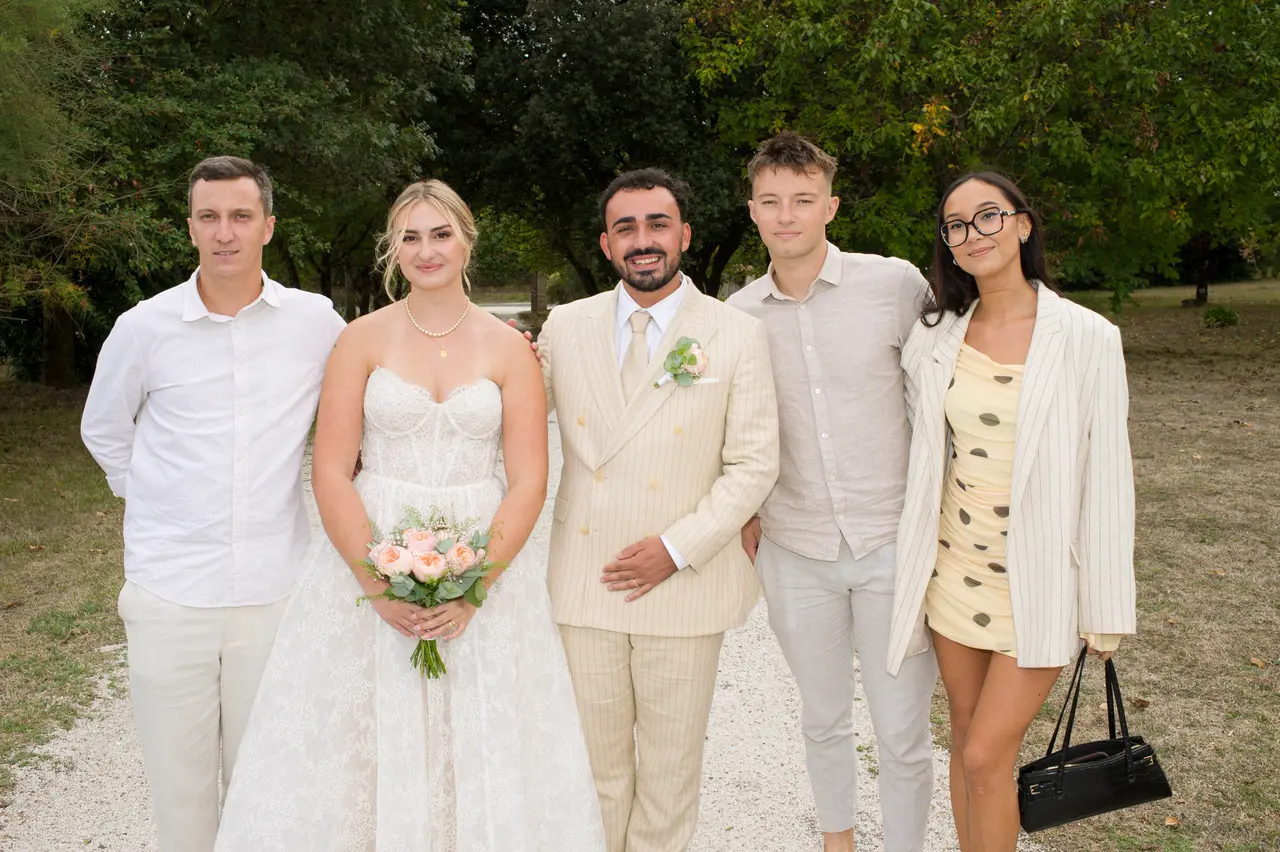 les mariés avec deux hommes en chemises claires et une femme en robe jaune à pois