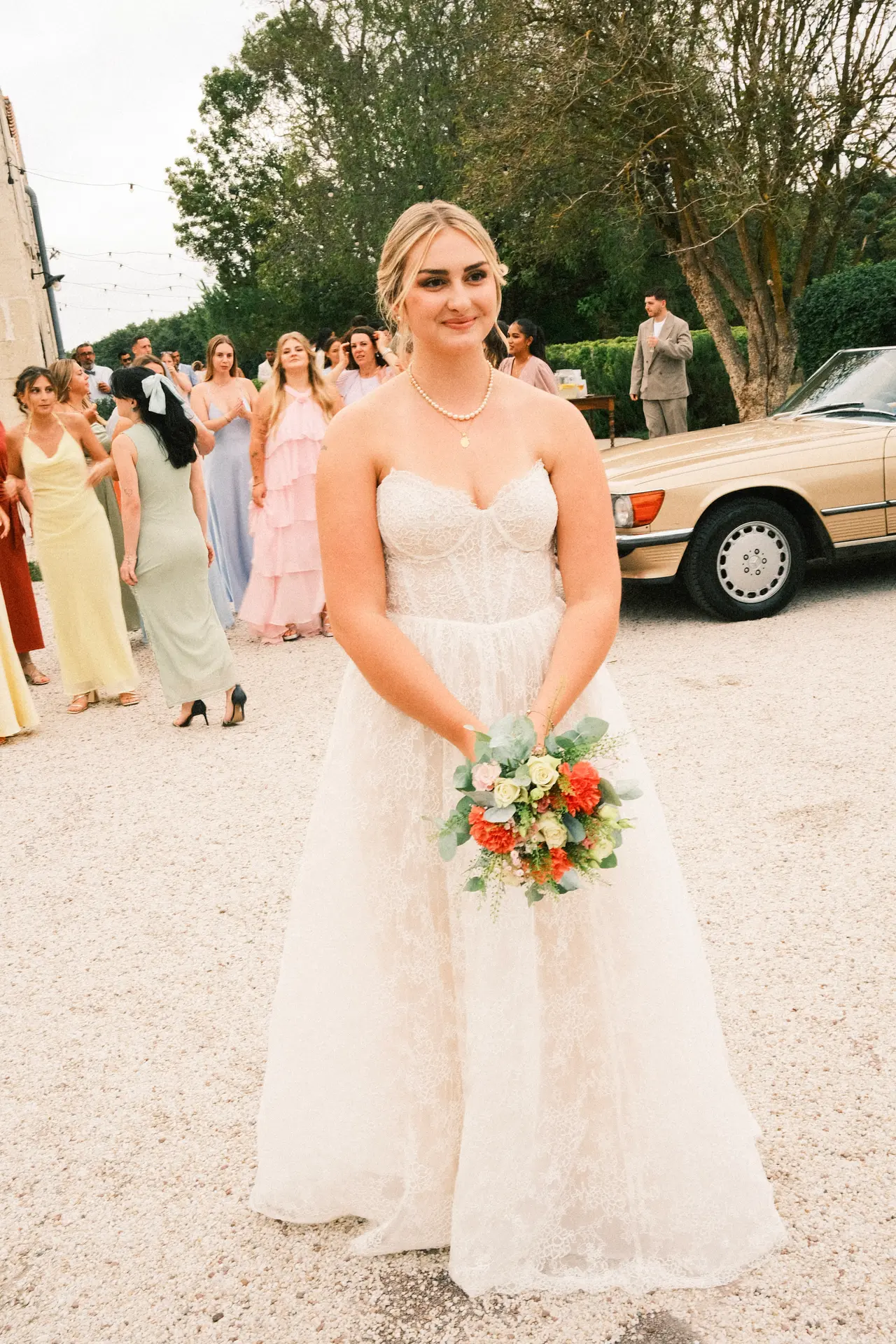 la mariée seule, bouquet en main, foule derrière