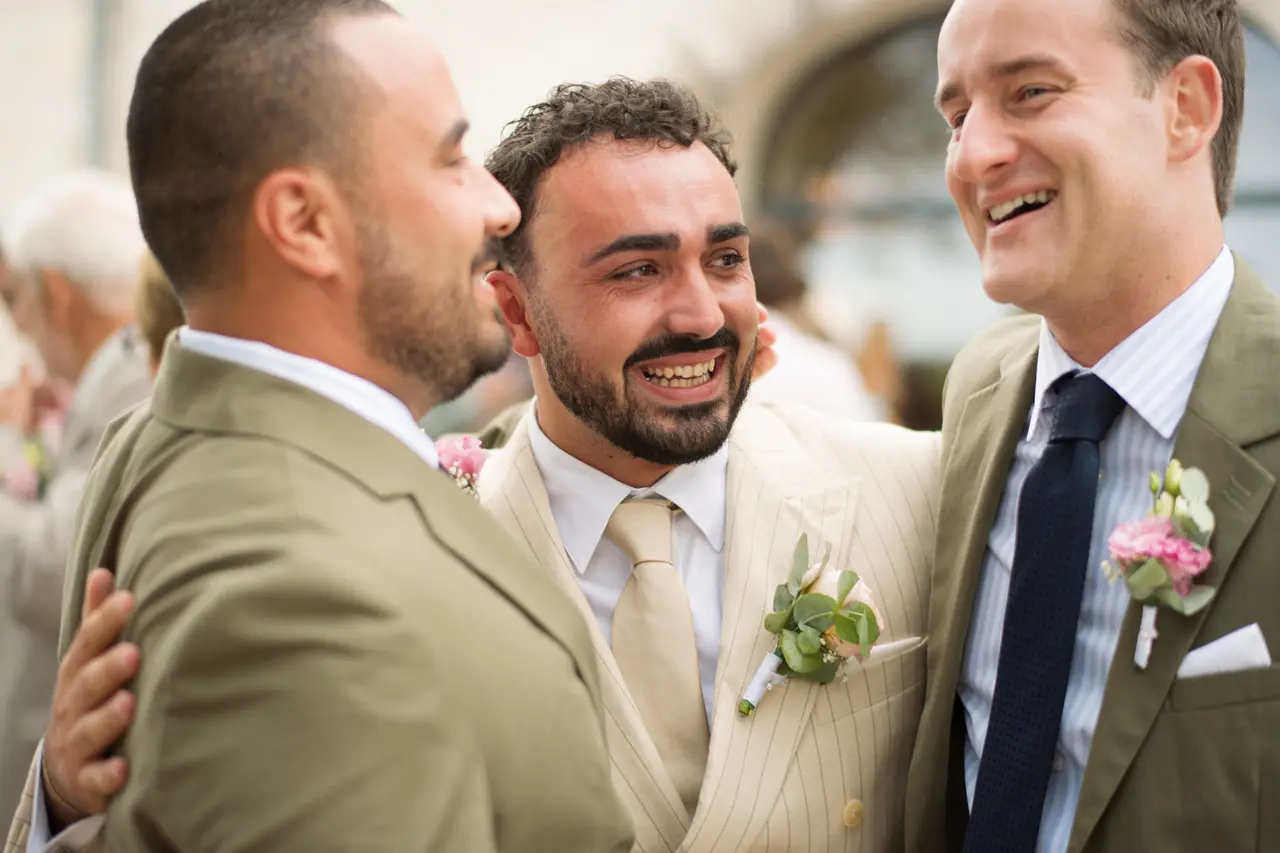 trois amis hilares joue contre joue, boutonnières fleuries