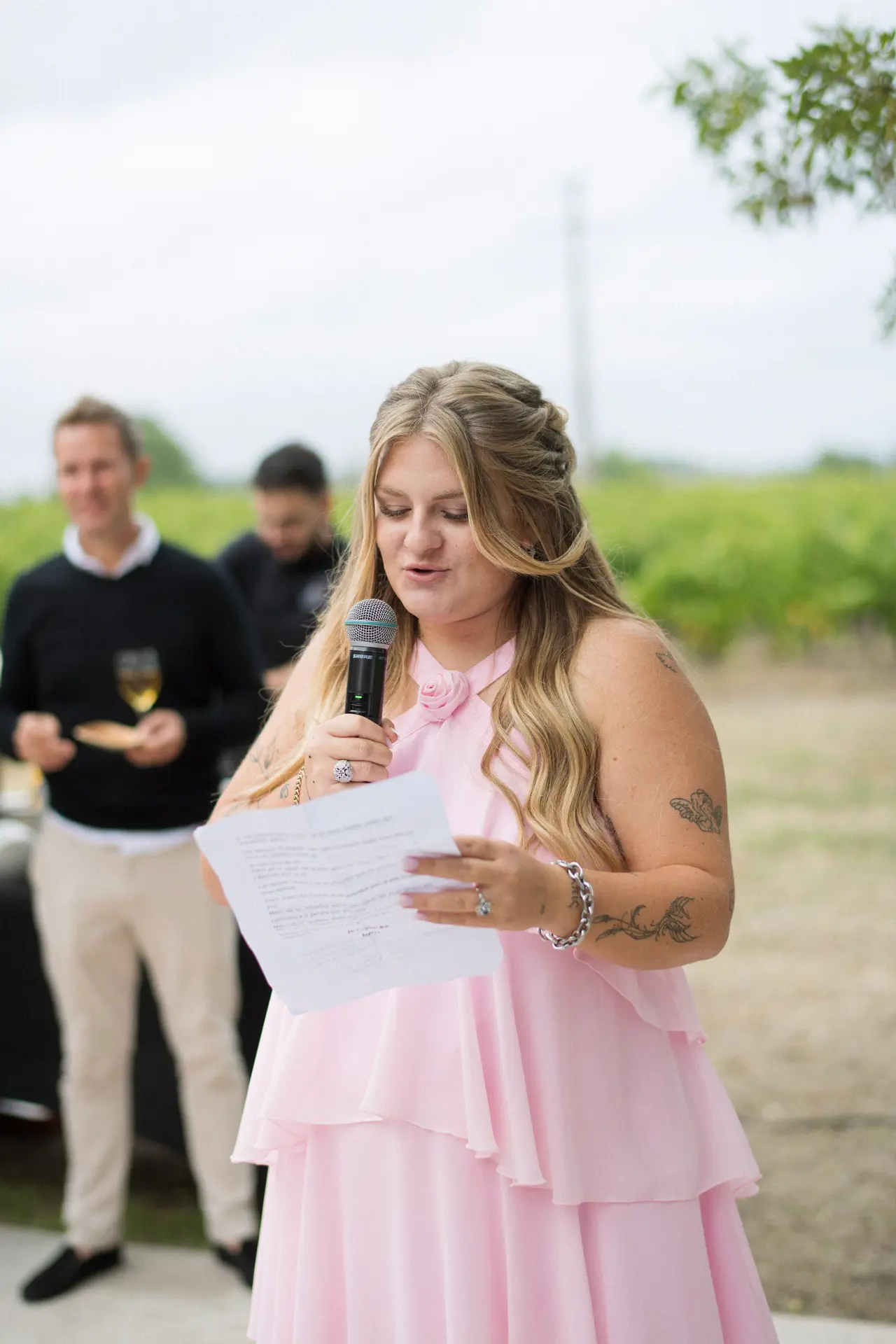 l'amie en robe rose lit son discours au micro