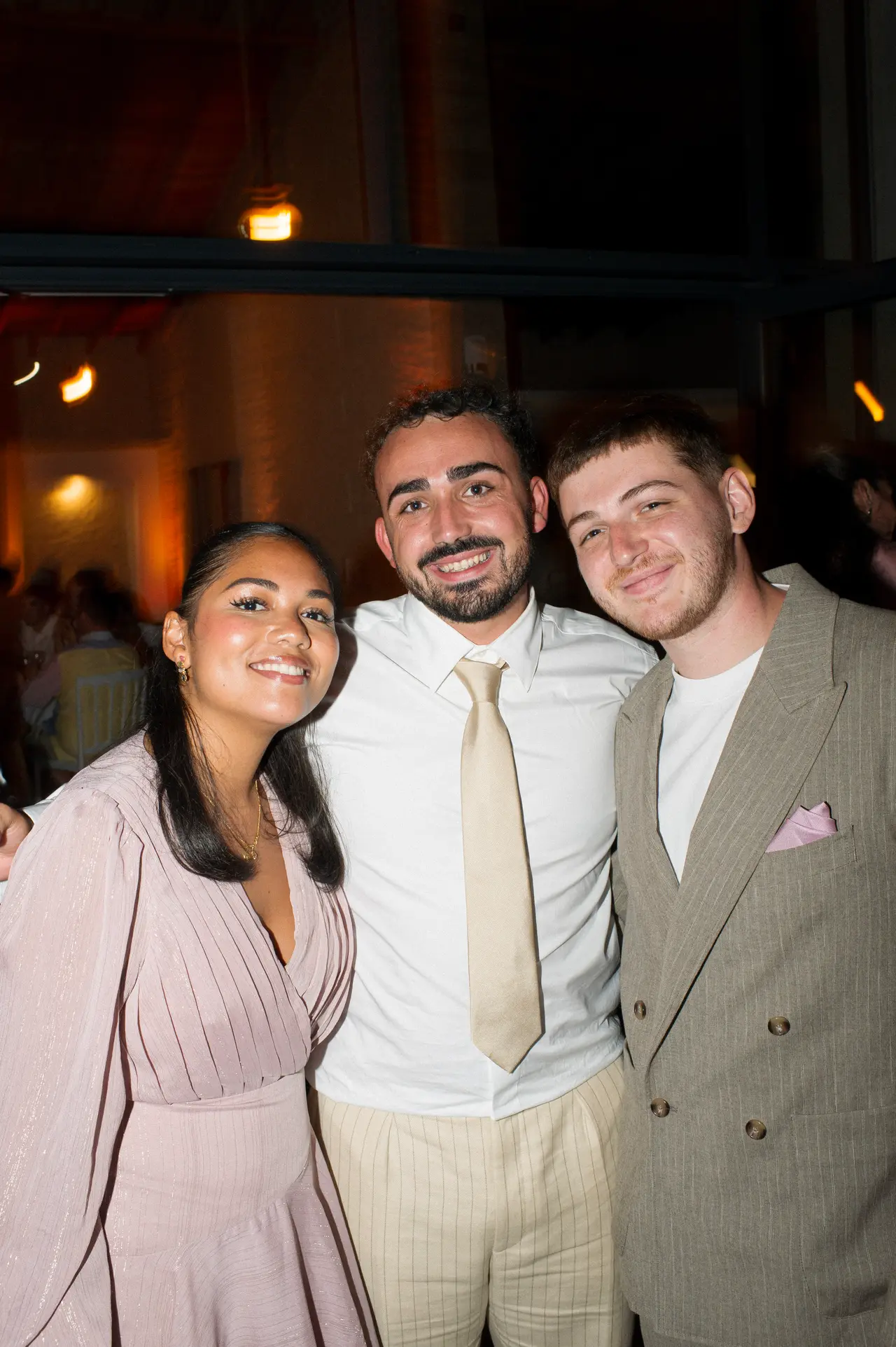 trio d'invités serrés, sourires, décor de pierre