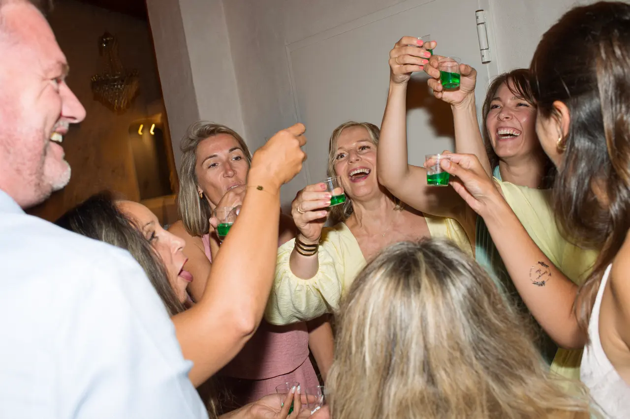 tournée de shots verts, bras levés et verres qui trinquent