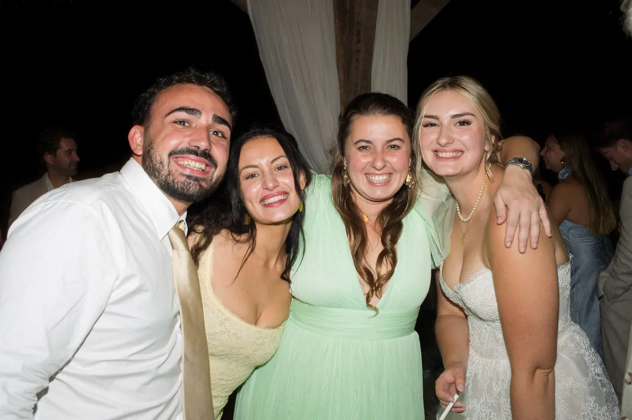 Les mariés serrés avec deux invitées en robes jaune et vert d'eau, de nuit