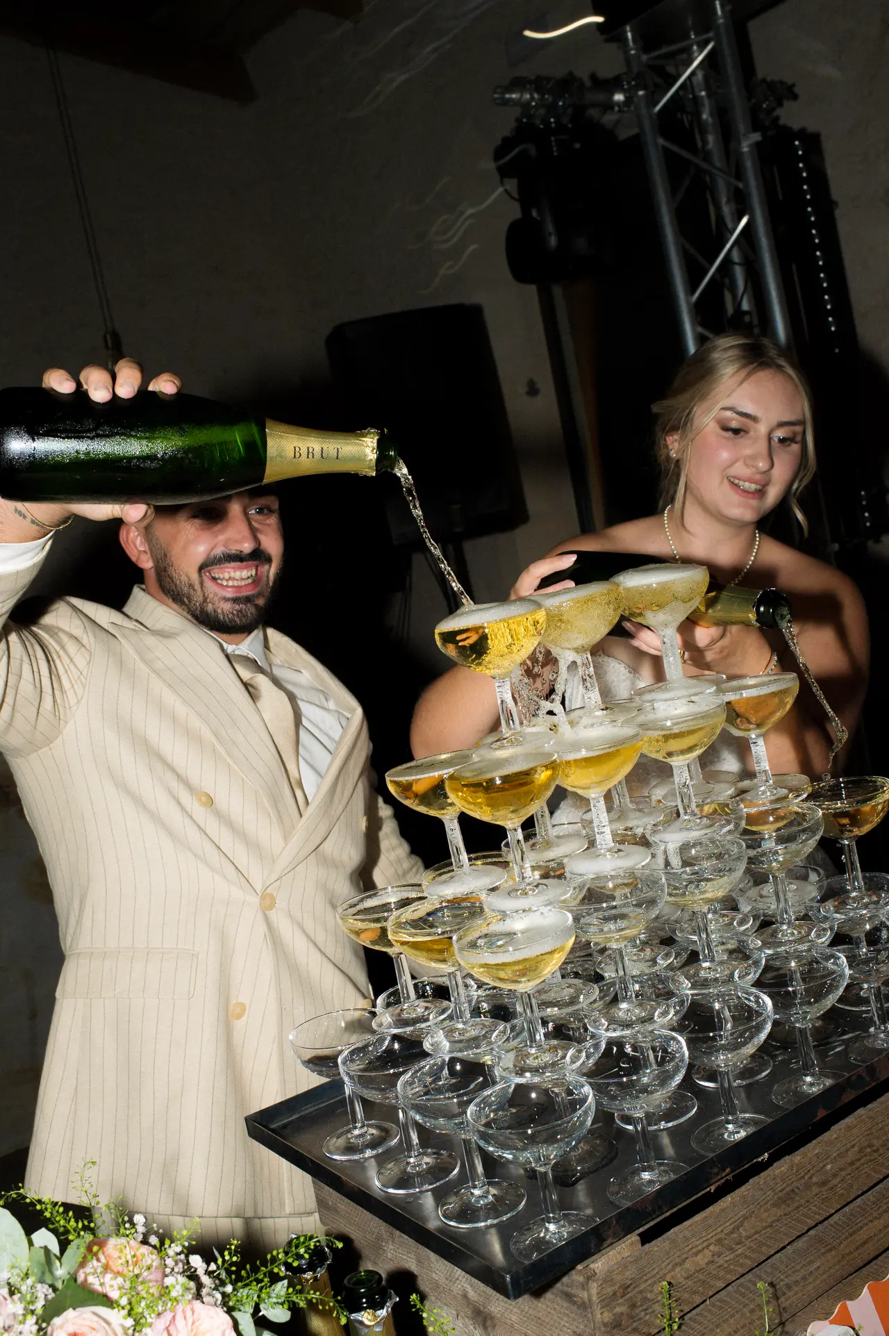 le marié verse le champagne en haut de la pyramide, sourire radieux