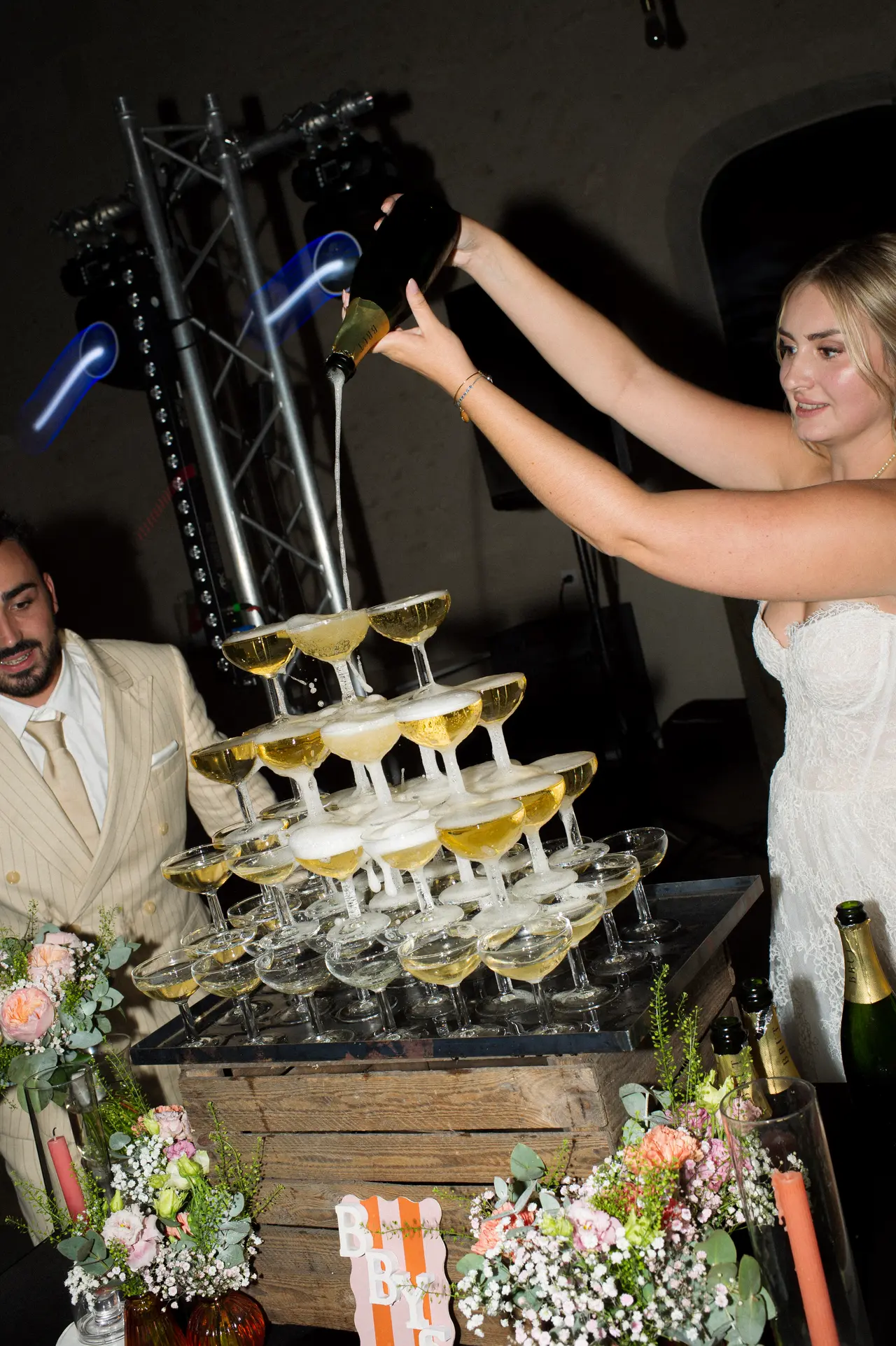 la mariée verse à bout de bras, geste ample au-dessus des coupes
