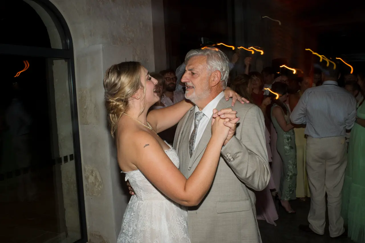 la mariée danse avec un invité, cierges magiques en arrière-plan