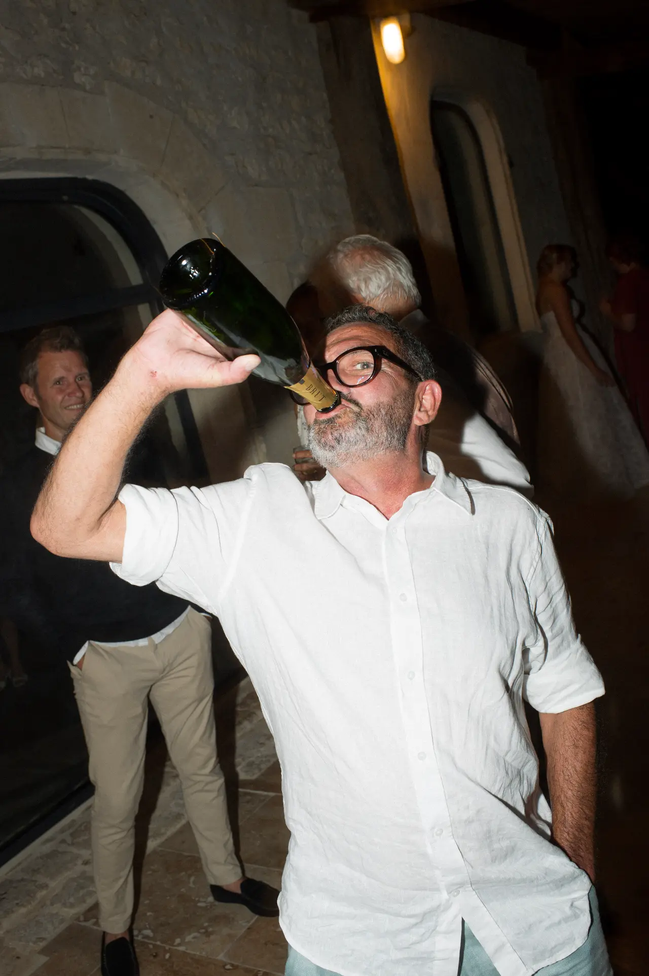 un invité boit la bouteille de champagne au goulot, tête en arrière
